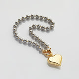 Велике золоте серце на сірих перлах